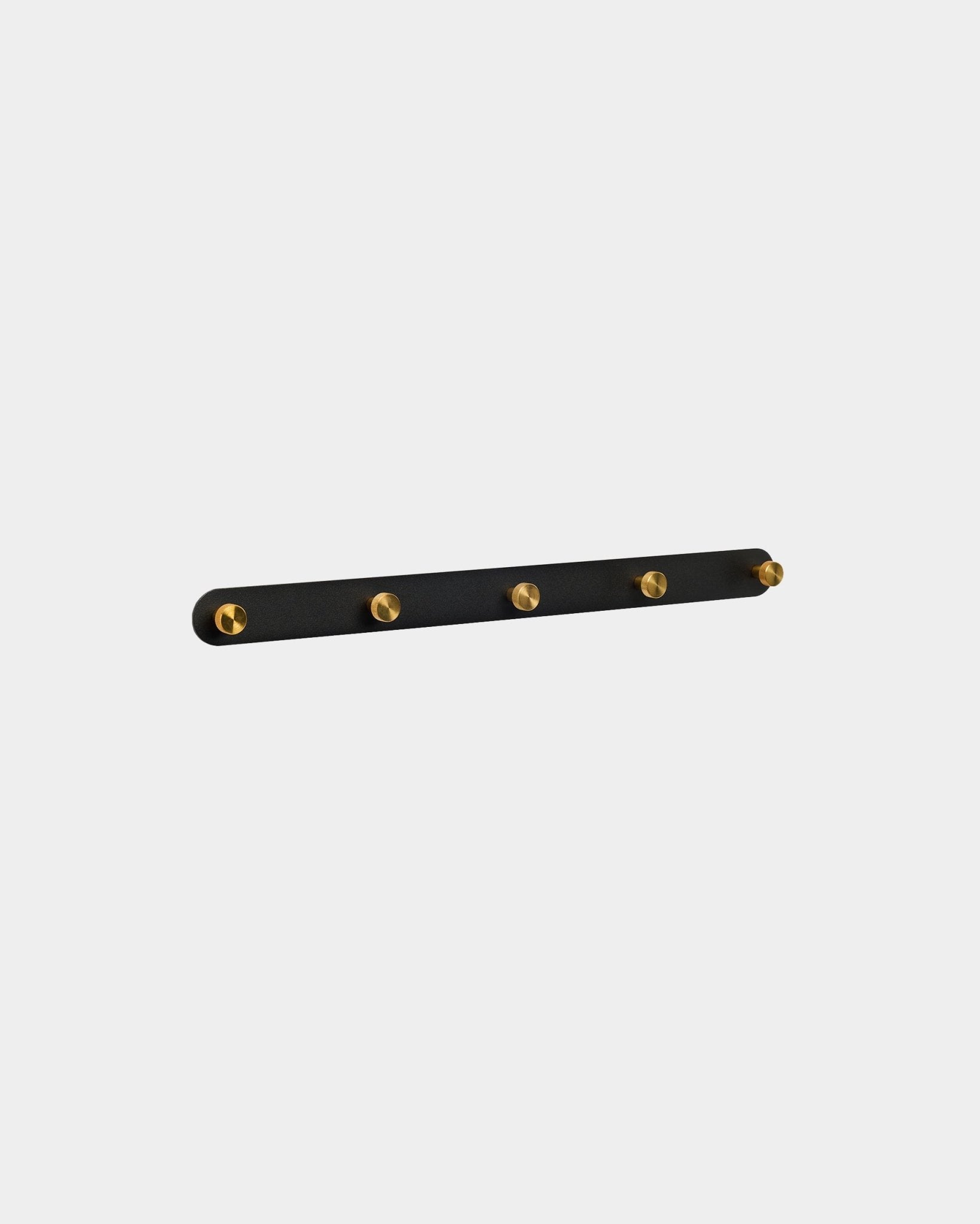 Perchero de pared WoodUpp Norr en black y brass con 5 ganchos de steel, montado en la pared, presentado sobre un fondo blanco liso.
